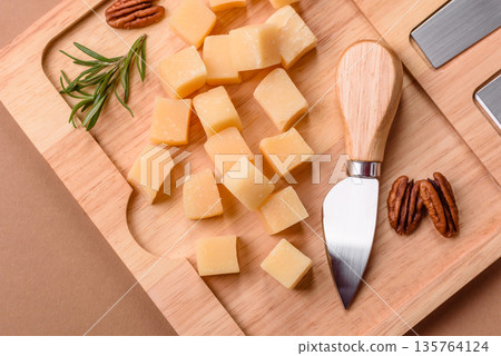 Cubed cheddar, gouda, or parmesan cheese on a cutting board. Cubed cheese 135764124