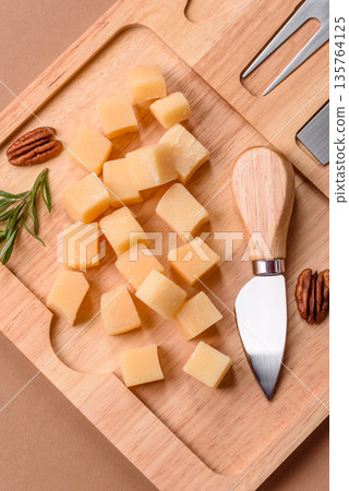 Cubed cheddar, gouda, or parmesan cheese on a cutting board. Cubed cheese 135764125