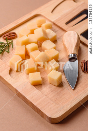 Cubed cheddar, gouda, or parmesan cheese on a cutting board. Cubed cheese 135764126