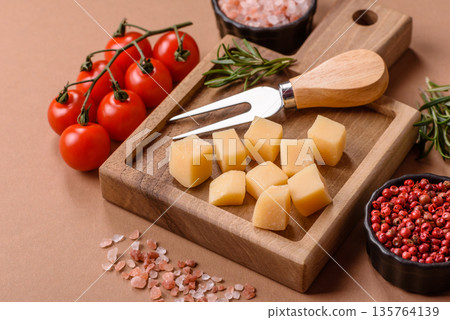 Cubed cheddar, gouda, or parmesan cheese on a cutting board. Cubed cheese 135764139