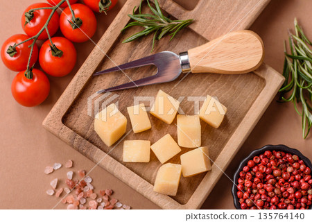 Cubed cheddar, gouda, or parmesan cheese on a cutting board. Cubed cheese 135764140