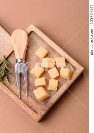 Cubed cheddar, gouda, or parmesan cheese on a cutting board. Cubed cheese Cubed cheddar, gouda, or parmesan cheese on a cutting board. Cubed cheese 135764145