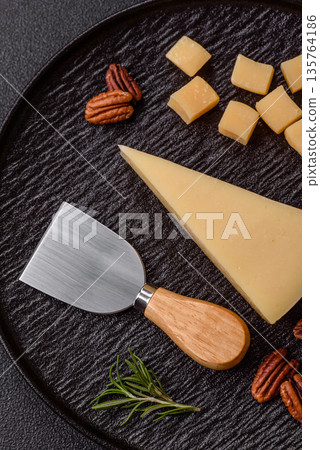A wedge of cheddar, gouda, or parmesan cheese on a cutting board. Cheese wedge 135764186