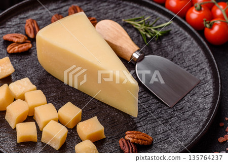 A wedge of cheddar, gouda, or parmesan cheese on a cutting board. Cheese wedge 135764237