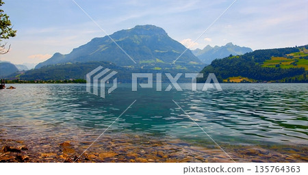 Serene Lake With Peaks Reflected, Calm Mountain Backdrop With Shimmering Water And Colorful Skies Serene Lake With Peaks Reflected, Calm Mountain Backdrop With Shimmering Water And Colorful Skies 135764363