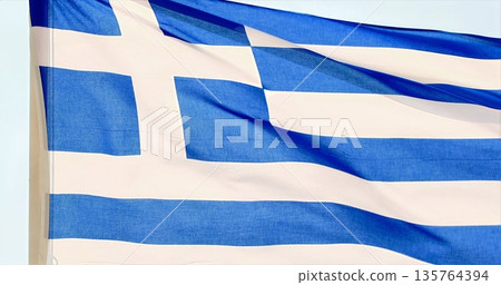 Sunlit Greek Flag Dances Over Azure Waters, Azure Sea Beneath Waving Greek Flag With Sunlight Overhead 135764394
