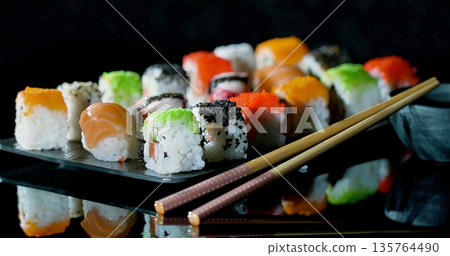 Collection Of Vividly Colored Sushi Artfully Positioned On Shiny Dark Base With Soft Lighting For Atmosphere 135764490