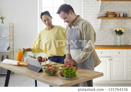 Couple cooking healthy salad for breakfast together at home, follow tablet recipe Couple cooking healthy salad for breakfast together at home, follow tablet recipe 135764536