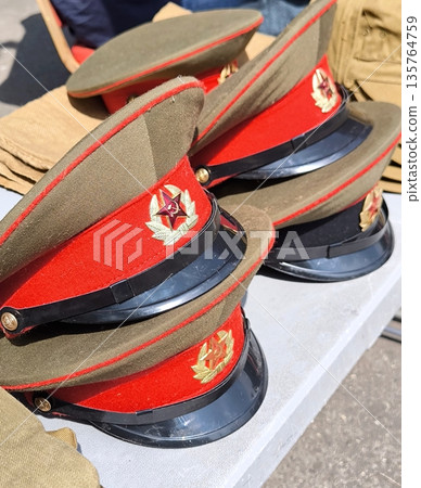 Military caps with red bands and cockades with a star, lying in a stack on the table Military caps with red bands and cockades with a star, lying in a stack on the table 135764759