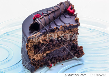 Exquisite dessert with chocolate glaze, decor, and berries. Close-up of a cake slice showing layers of delicate sponge and cream. Perfect for cafe menus and food blogs 135765285