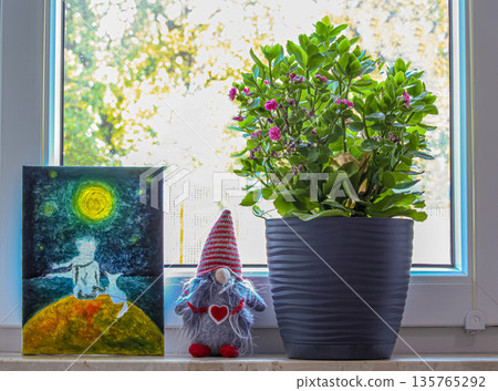 Cozy interior composition on a window. A painting of the Little Prince, a textile gnome with a heart, and green Kalanchoe create an atmosphere of warmth and creativity on a sunny spring day 135765292