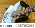 Detailed view of an electric guitar body and fretboard with a yellow pick. The instrument lies on parquet, creating a cozy atmosphere of a home studio or spring music practice 135765293