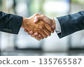 Hands of a businessman in a suit shaking hands in a business office to sign a contract 135765587