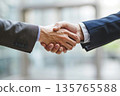 Hands of a businessman in a suit shaking hands in a business office to sign a contract 135765588