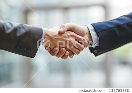Hands of a businessman in a suit shaking hands in a business office to sign a contract 135765588