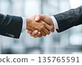 Hands of a businessman in a suit shaking hands in a business office to sign a contract 135765591