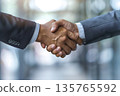 Hands of a businessman in a suit shaking hands in a business office to sign a contract 135765592