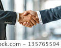 Hands of a businessman in a suit shaking hands in a business office to sign a contract 135765594