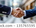 Hands of a businessman in a suit shaking hands in a business office to sign a contract 135765595