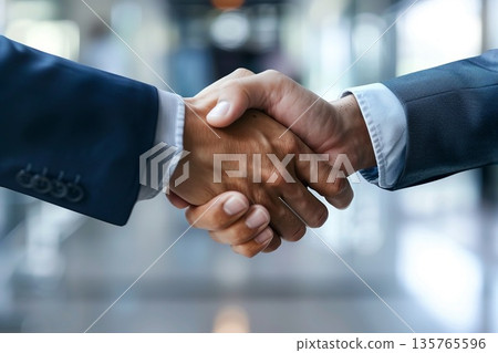 Hands of a businessman in a suit shaking hands in a business office to sign a contract 135765596