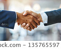 Hands of a businessman in a suit shaking hands in a business office to sign a contract 135765597