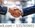Hands of a businessman in a suit shaking hands in a business office to sign a contract 135765601