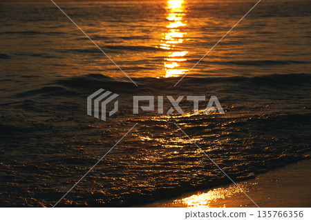 Vlora, Albania August  2025 Sunset reflections on the shoreline as gentle waves wash over the sand, capturing warm golden light and peaceful evening scenery on the Adriatic coast. 135766356