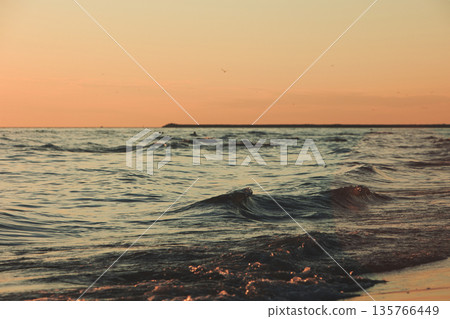 Vlora, Albania  August , 2025 Sunset reflections on the shoreline as gentle waves wash over the sand, capturing warm golden light and peaceful evening scenery on the Adriatic coast. 135766449