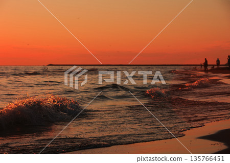 Vlora, Albania  August , 2025 Sunset reflections on the shoreline as gentle waves wash over the sand, capturing warm golden light and peaceful evening scenery on the Adriatic coast. 135766451