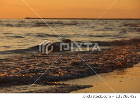 Vlora, Albania  August , 2025 Sunset reflections on the shoreline as gentle waves wash over the sand, capturing warm golden light and peaceful evening scenery on the Adriatic coast. 135766452