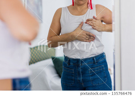 Woman checking breast for lumps cancer self examination 135766476