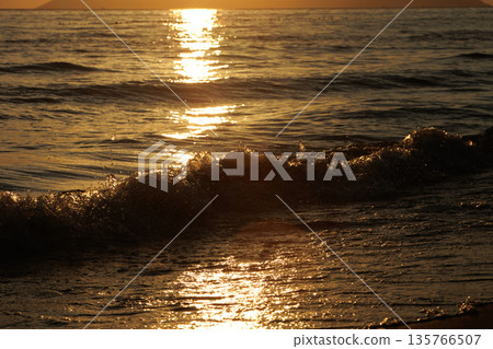 Vlora, Albania  August , 2025 Sunset reflections on the shoreline as gentle waves wash over the sand, capturing warm golden light and peaceful evening scenery on the Adriatic coast. 135766507