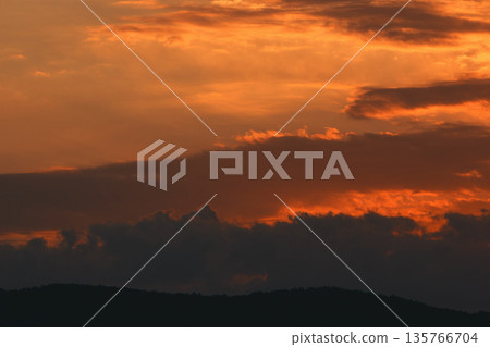 Soft golden sunset clouds over Vlora, Albania on August 2025, with a lone bird gliding across the sky in a peaceful minimalistic scene. 135766704