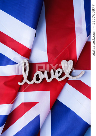 Wooden word love on National symbol of Great Britain. British full framed wave UK fabric flag background. Copy space for your text. Independence Wooden word love on National symbol of Great Britain. British full framed wave UK fabric flag background. Copy space for your text. Independence 135766977