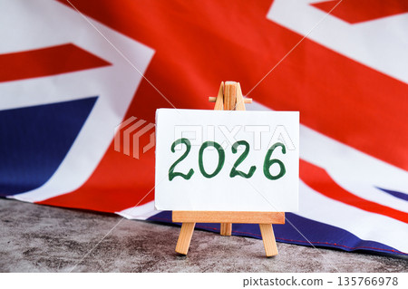 Paper note with text 2026 on National symbol of Great Britain. British wave the UK silky flag background. Financial outlook planning, new year annual report Paper note with text 2026 on National symbol of Great Britain. British wave the UK silky flag background. Financial outlook planning, new year annual report 135766978