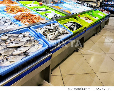 Fish displayed in a store with various types laid out on ice. Fish displayed in a store with various types laid out on ice. 135767270