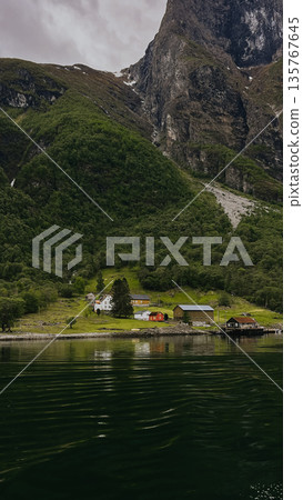 A mountain with waterfall and houses in the background Houses are on the right side of the waterfall 135767645