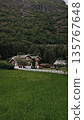 Red house in mountains. Green hills, clear sky, peaceful Nordic landscape.  135767648
