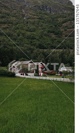 Red house in mountains. Green hills, clear sky, peaceful Nordic landscape. Red house in mountains. Green hills, clear sky, peaceful Nordic landscape. 135767648