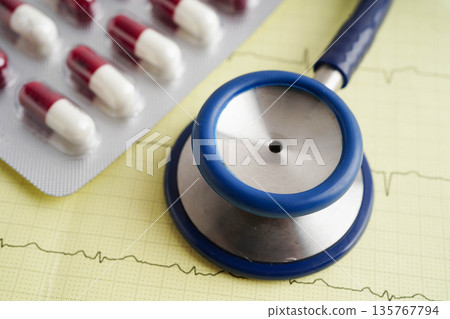 Stethoscope on electrocardiogram ECG with capsule drug, heart wave, heart attack, cardiogram report. Stethoscope on electrocardiogram ECG with capsule drug, heart wave, heart attack, cardiogram report. 135767794