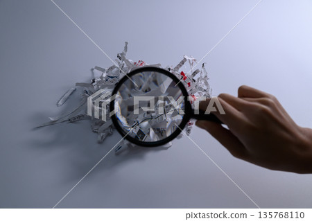 一手拿放大鏡檢查碎紙 135768110