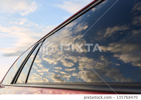美麗的日落和金色的雲彩倒映在車窗上。 美麗的日落和金色的雲彩倒映在車窗上。 135768470