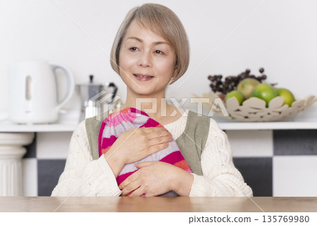 廚房裡,一位老婦人正往熱水袋裡倒熱水。 廚房裡,一位老婦人正往熱水袋裡倒熱水。 135769980