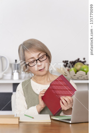 Senior woman keeping household accounts in the kitchen 135770099