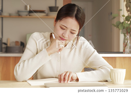 A young woman writing while thinking A young woman writing while thinking 135771029