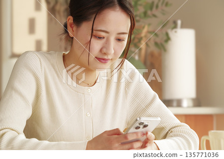A woman looking at her smartphone while relaxing 135771036