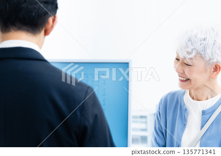 一位資深女性正在櫃檯辦理手續。 135771341