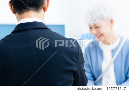 一位資深女性正在櫃檯辦理手續。 135771347