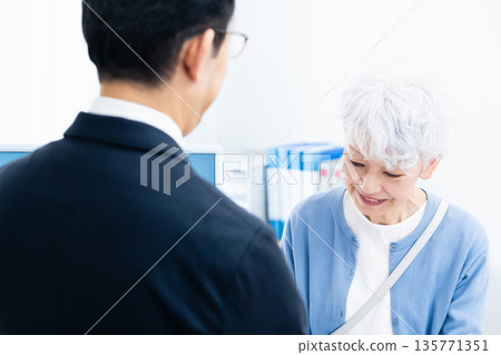一位資深女性正在櫃檯辦理手續。 135771351