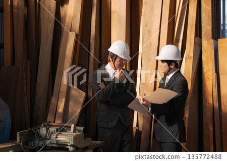 Men in suits looking at lumber at a lumberyard 135772488